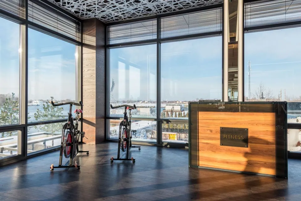 Wooden gym reception desk beside spin bikes and windows