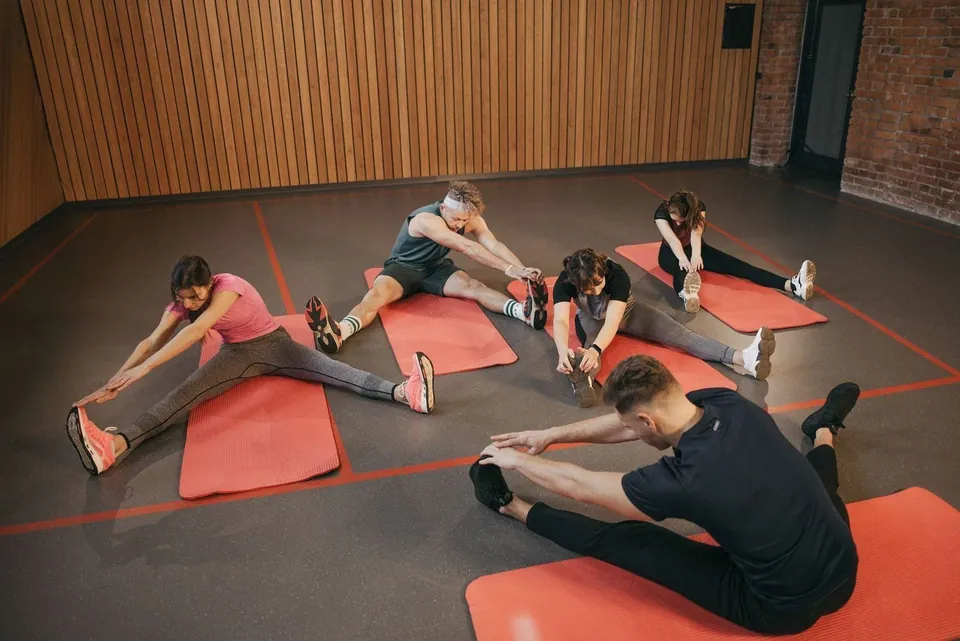 Group fitness class stretching on red mats in a studio