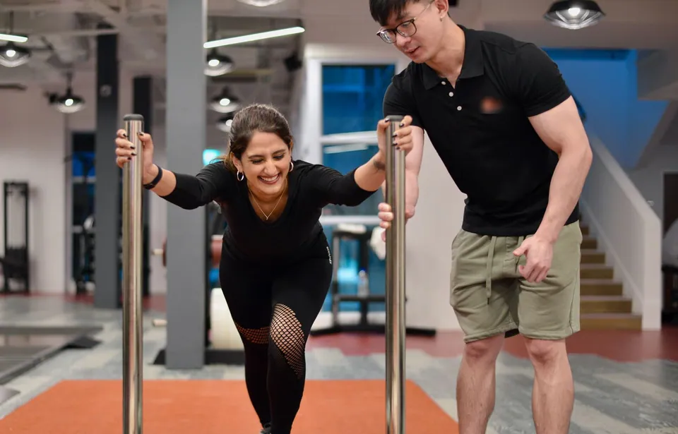 Personal trainer coaching a woman pushing a gym sled